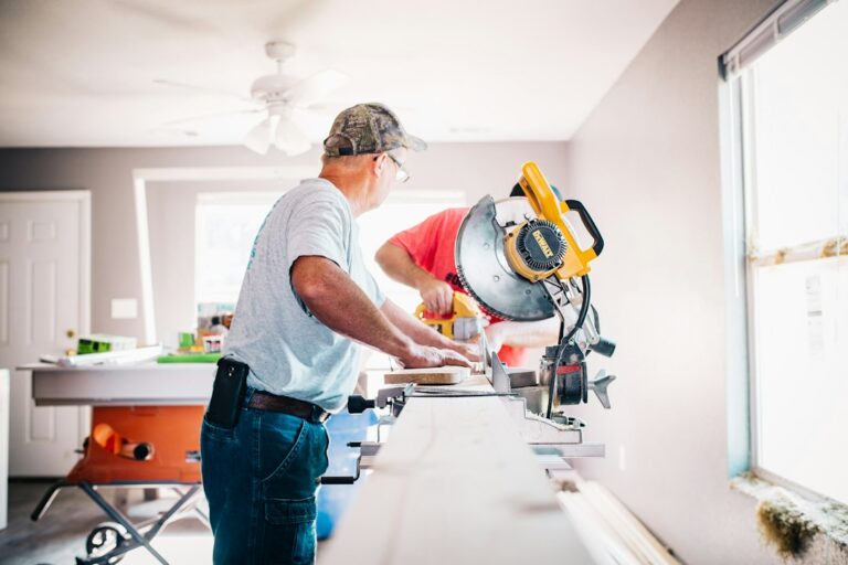 Homeowners review a remodeling plan beside a protected kitchen work area with tools and building materials.