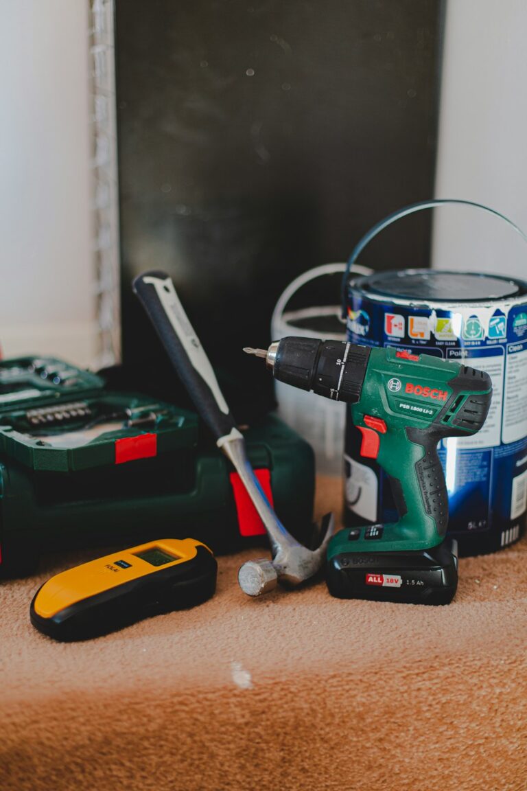 A homeowner using a tape measure for a shelving project with tools and instructions on a kitchen table.